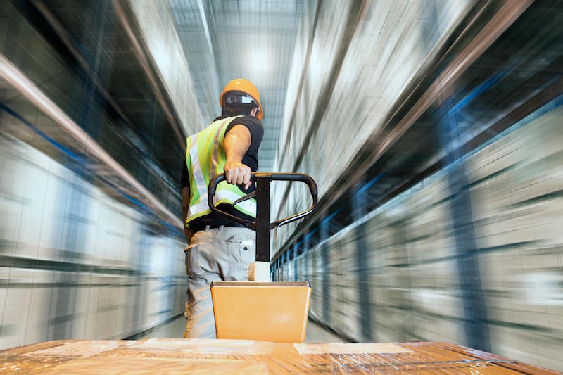 Employee moving pallet at super speed for improved efficieny in warehouse.